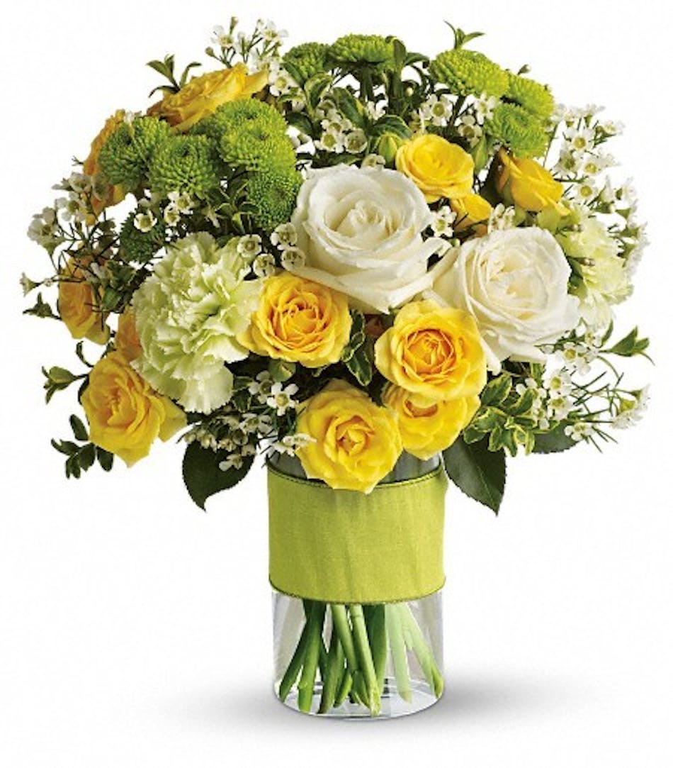 White and yellow roses and other s in a glass cylinder vase.